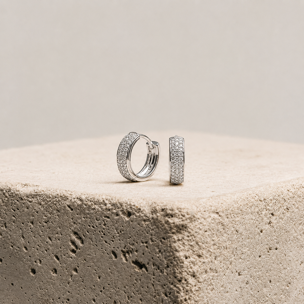 Pair of silver hoop earrings on a textured surface with a neutral background